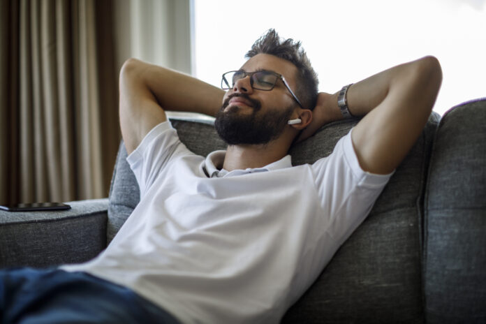 Young man with bluetooth headphones relaxing on sofa