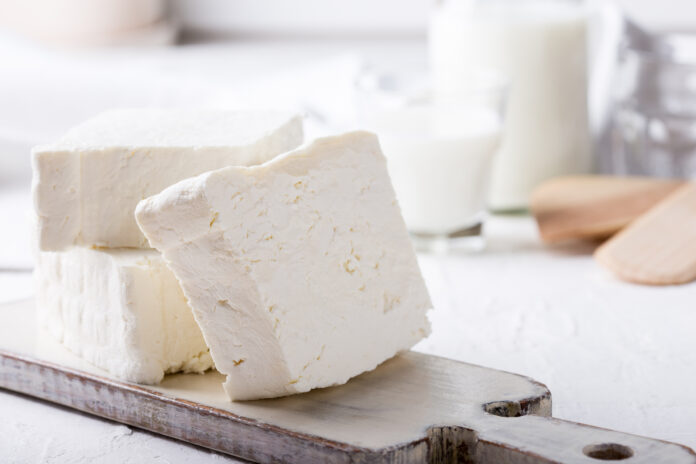 Fresh cottage cheese on rustic white wooden board