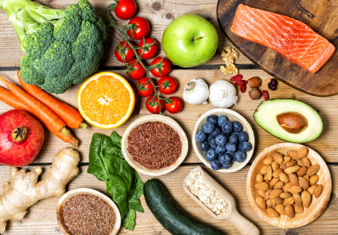 Healthy food clean eating selection: fruit, vegetable, seeds, superfood, cereal, leaf vegetable on gray concrete background