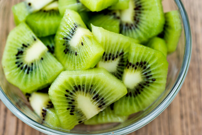 A bowl of kiwi fruit slices on wooden table