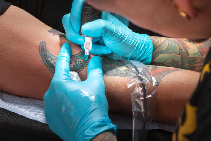 Tattoo artist tattooing a young man's arm