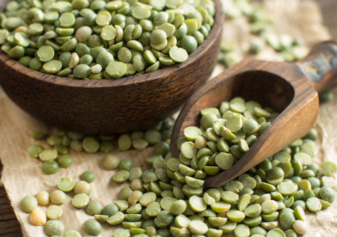 Uncooked Green Split Peas in a bowl with a spoon