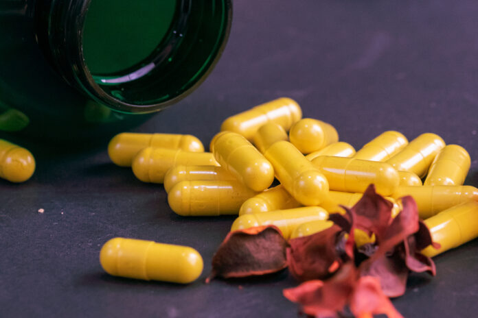 Green bottle of supplements with yellow capsules on a black background Berberine