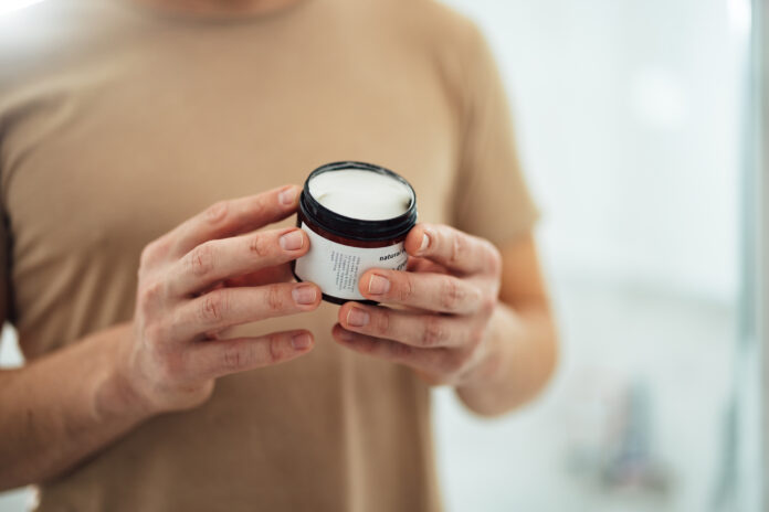 Anonymous Man Holding Face Cream in the Bathroom (Copy Space) personal care product expiration