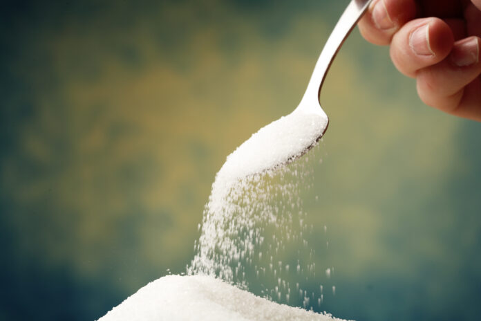 Spoon dumping sugar into a pile added sugars