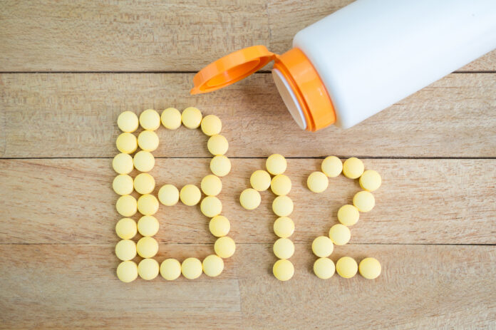 Yellow pills forming shape to B12 alphabet on wood background vitamin B12